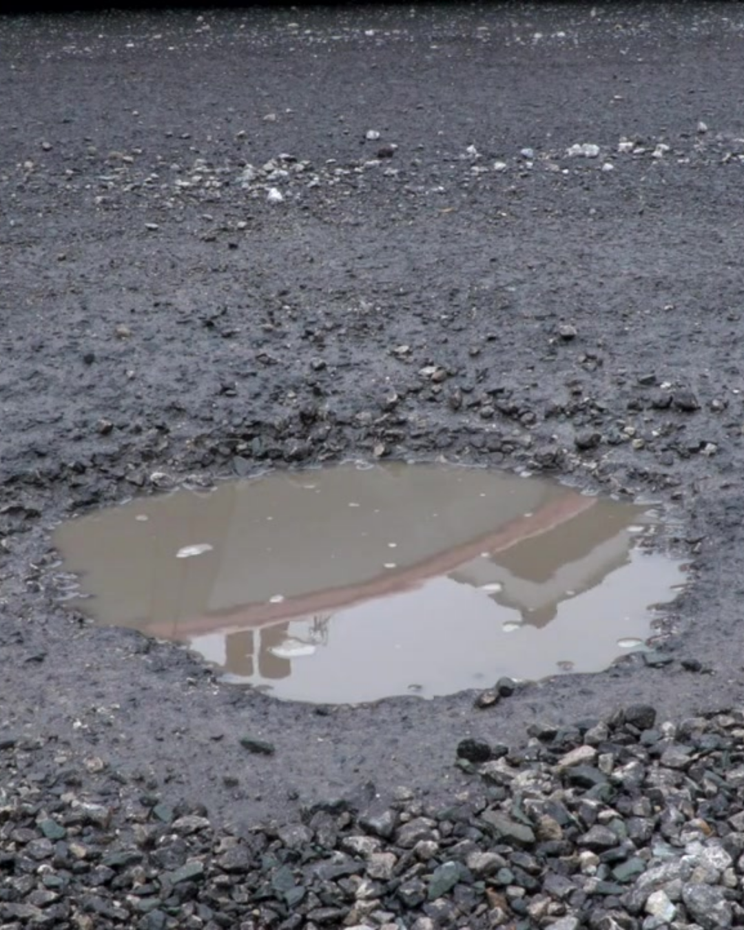 Photo of a pothole with a puddle in it