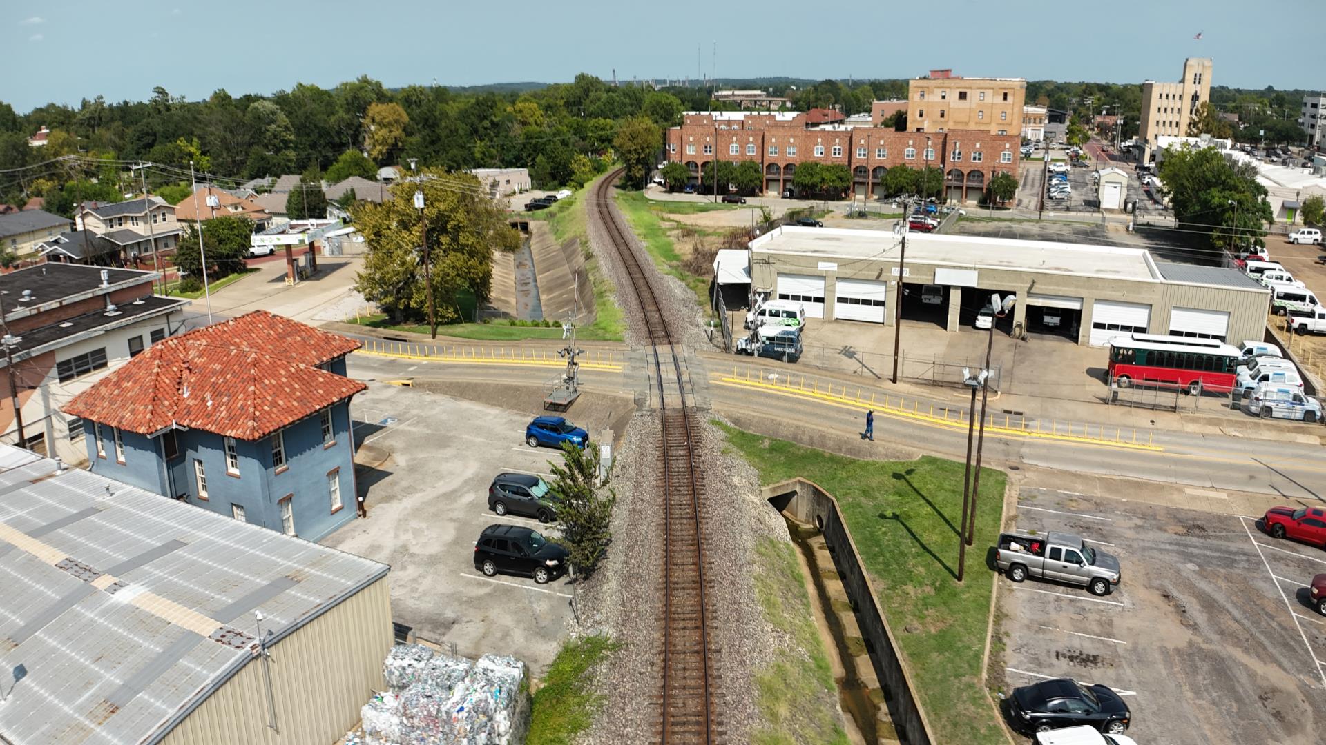 A view of the railroad tracks crossing East Locust Street in Tyler, showing nearby buildings, vehicles, and Downtown Tyler.