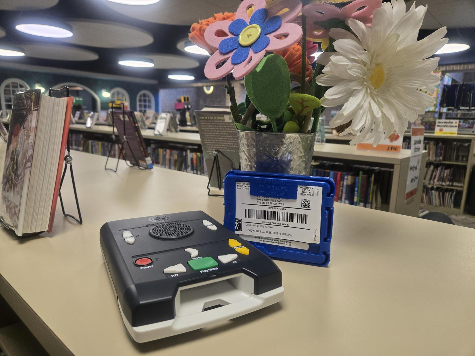 Photo showing Talking Book device with library book shelves in the background